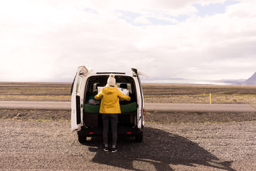 Woman looking at a map on the back of a camper van