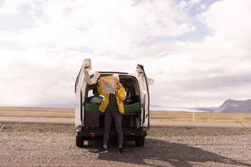 Woman standing by van looking at a map