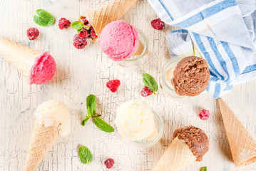 Summer sweet berries and desserts, various of ice cream flavor in cones pink (raspberry), vanilla and chocolate with mint on light concrete background copy space