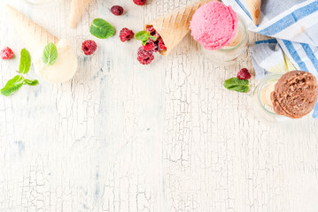 Summer sweet berries and desserts, various of ice cream flavor in cones pink (raspberry), vanilla and chocolate with mint on light concrete background copy space