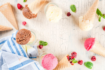 Summer sweet berries and desserts, various of ice cream flavor in cones pink (raspberry), vanilla and chocolate with mint on light concrete background copy space