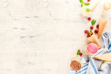 Summer sweet berries and desserts, various of ice cream flavor in cones pink (raspberry), vanilla and chocolate with mint on light concrete background copy space