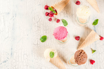 Summer sweet berries and desserts, various of ice cream flavor in cones pink (raspberry), vanilla and chocolate with mint on light concrete background copy space