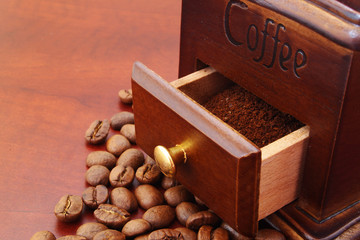 Wooden manual coffee grinder with coffee beans on table