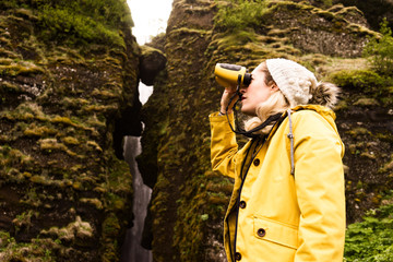 Woman looking through binoculars in countryside