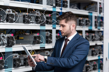 serious young businessman using tablet at ethereum mining farm