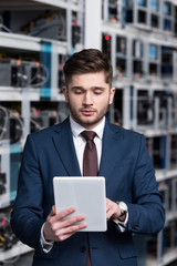 handsome young businessman using tablet at ethereum mining farm
