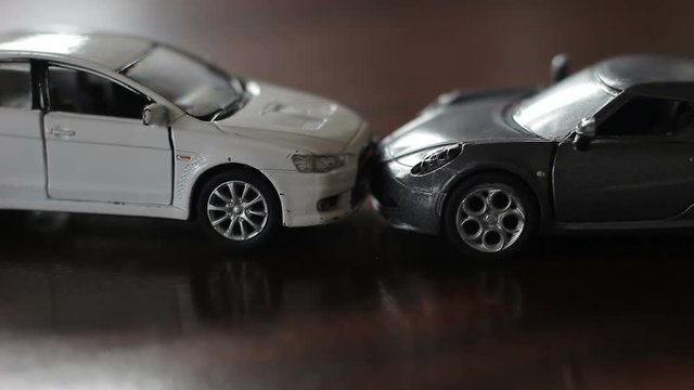 Head-on collision of two toy cars. Accident of a white and gray car
