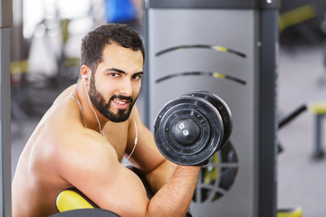 Fototapeta na wymiar Bearded topless man wears black sport gloves have biceps workout in the gym