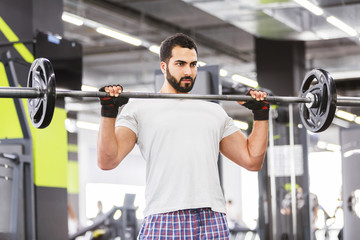 Bearded muscular man wears white t-shirt have workout with barbell in the gym