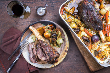 Venison knuckle with fried potatoes and vegetable as top view in a casserole and on a plate