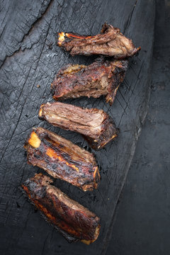 Barbecue spare ribs St Louis cut with hot honey chili marinade sliced as top view on an old burnt board with copy space