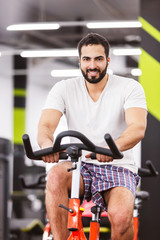 Muscular man cycling on exercise bike in the gym