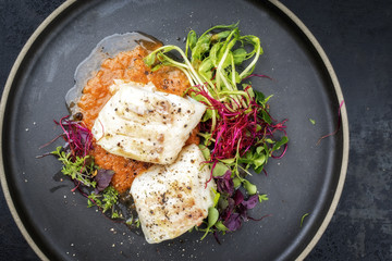 Steamed cod fish filet with lettuce as top view on a plate with copy space left