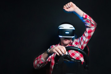 The joyous man sits in the VR glasses and plays the race on the simulator of the car. A happy gamer plays a race with a VR headset. Victory in the game © bodnarphoto