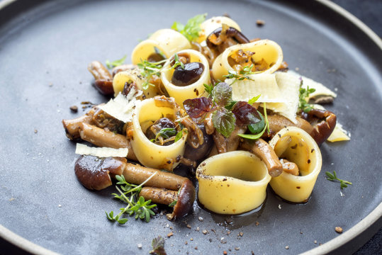 Traditional Italien calamarata noodles with mushroom and parmesan as close up on a plate