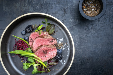 Traditional barbecue aged sliced fillet steak with wild garlic and fruits top view on a plate with...