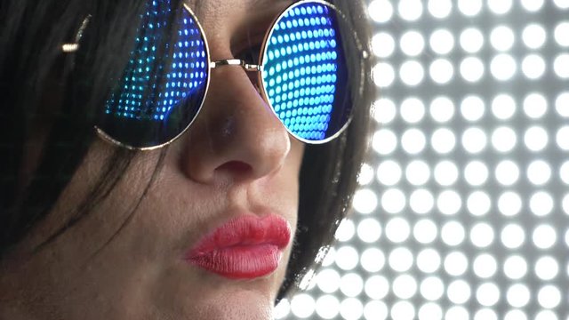 Hot brunette in round sunglasses, chewing gum and blowing a bubble. 4k, slow motion.
