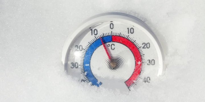 Outdoor thermometer in the snow shows decreasing temperature - cold winter weather change concept