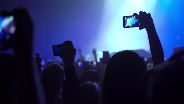 People at the concert in club, shooting stage on mobile phone
