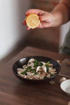 Cook preparing salad with mushrooms and herb