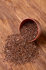 An overturned ceramic bowl with linseeds on a rustic background, close-up, shallow depth of field, selective focus
