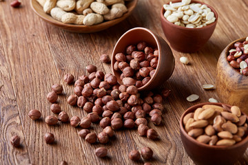 A composition from different varieties of nuts in a wooden bowls on rustic background, close-up, shallow depth of field