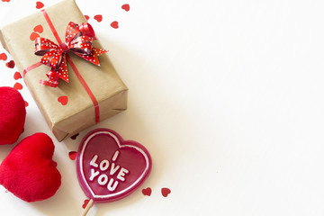 Gift box, fluffy hearts and heart-shaped lollipop wiht I love you text on white wooden background. Copy space.