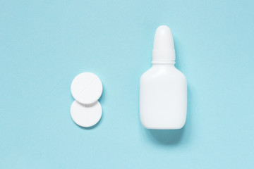Nasal drops and white pills on blue background. Mock up. Concept flu, colds, runny nose