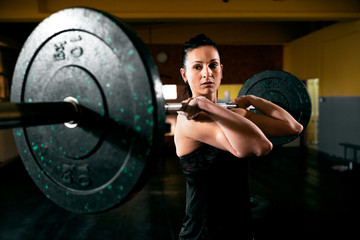 Fototapeta na wymiar Exercise with heavy weight, muscular girl holding weights and training hard