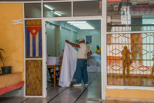 Street Laundry. The man stands with his back and straightens the white fabric.. Havana. Cuba