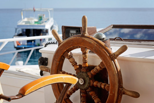 yacht's wooden steering wheel in the blue sea