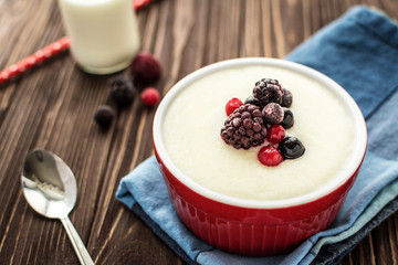 Semolina porridge with raspberries on rustic wooden background
