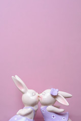 two porcelain rabbits are kissed on a pink background