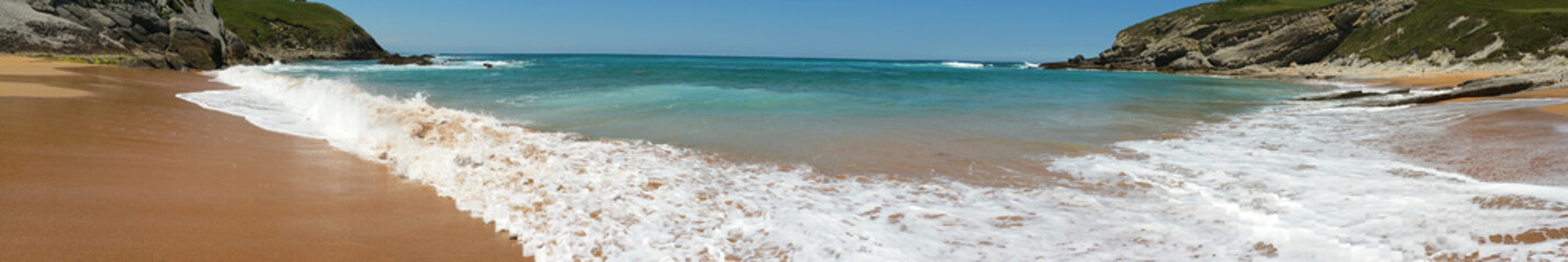 Beach with beautiful waves and blue sky, landscape. North Spain