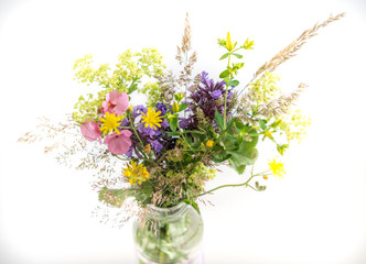 Ein selbstgepflückter Blumenstrauß in einer Vase aus Glas. Freigestellt. Weißer Hintergrund.