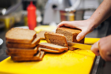 cook cuts bread in the kitchen