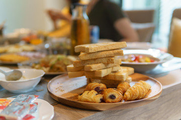 close up, pile of sliced wheat bread and french croissant in the wooden dish on the table for breakfast.