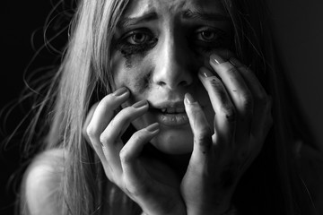 Crying young woman on a black background. Closeup. Black and white. Shallow depth of field