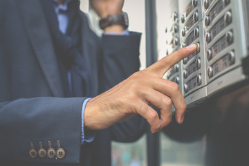 Businessman pushing bottom on building. Focus is on hand.