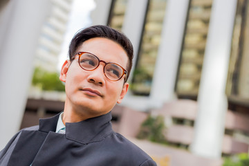 Asia young business man in front of the modern building in downtown .Concept of young  business people