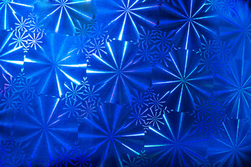 Abstract pattern background with round segments with rays on blue holographic paper.