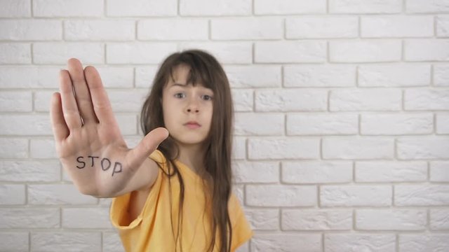 Child abuse. Domestic violence. A little girl shows an inscription on the hand of STOP.