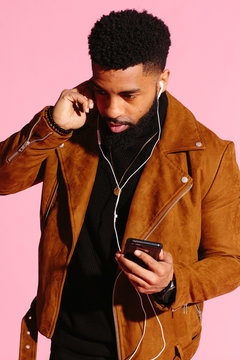 Cool African American man with beard holding his ear, listening,, isolated on pink studio background