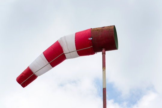 Red and white windsock, dramatic clouds, windy weather forecast concept