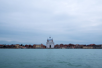 Fototapeta na wymiar Panoramic view of La Giudecca taken from the lagoon at dusk on a cloudy winter's day, showing Church of Santissimo Redentore in the centre of the photo.