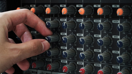 Closeup shot of Hand adjust the mid knob of analog mixer