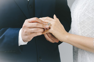 Newlyweds exchange rings, groom puts the ring on the bride's hand .