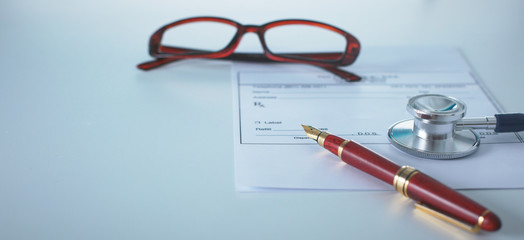 Doctor's workspace working table with patient's discharge blank paper form, medical prescription, stethoscope on desk