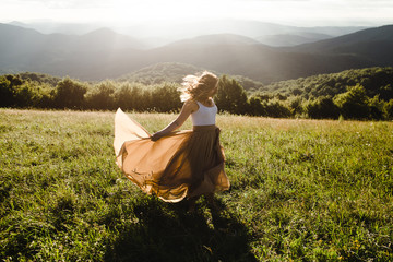 Woman with long dress running in a meadow in the mountains - 198627882